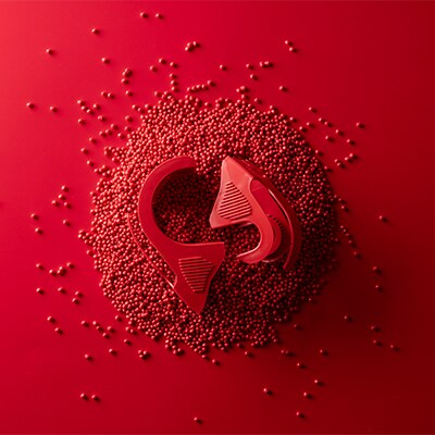 Roter Scotch™ Verpackungsklebebandabroller vor roten Perlen aus recyceltem Kunststoff