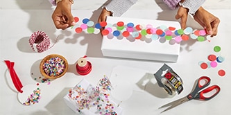 Verpacken einer Geschenkbox mit Konfetti-Klebeband, hergestellt durch Anbringen von buntem Konfetti auf Scotch® Klebeband
