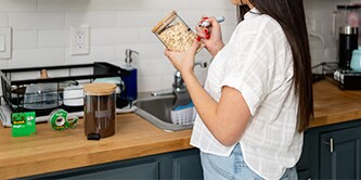 Frau, die Etiketten aus Scotch® Magic™ Klebeband auf Lebensmittelbehälter klebt

