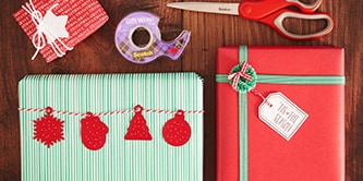 Ein traditionelles Weihnachtsgeschenkverpackungs-Aussehen mit roten, grünen und weißen Farben schaffen und Papierfiguren mit Scotch® doppelseitigem Klebeband befestigen
