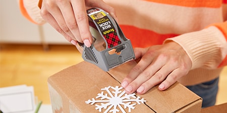 Ein Feiertagsgeschenk in einem Paket mit Scotch® Box Lock™ Klebeband versiegeln
