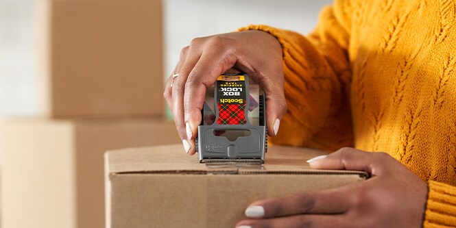 Frau, die Scotch Box Lock Verpackungsklebeband verwendet
