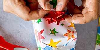 Sternenverpackungspapier verwenden und das Geschenkverpackungs-Aussehen mit einem Schleifenstern oben abschließen
