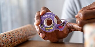 Ein Mann verpackt ein Geschenk mit Scotch® Geschenk-Klebeband
