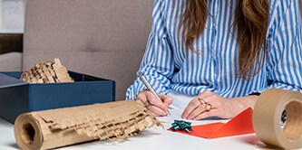 Frau verpackt sorgfältig ein Geschenk und verwendet Scotch™ Cushion Lock™ Schutzfolie

