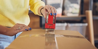 Frau versiegelt eine Schachtel mit Scotch® Verpackungsklebeband
